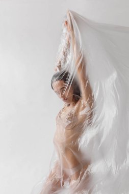 Plastik torba içindeki çıplak insanların stüdyo portresi, plastik kirlilik konsepti