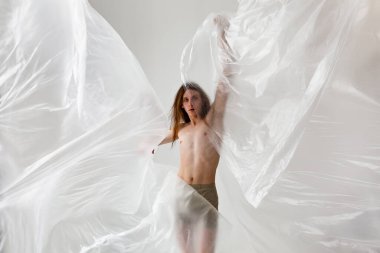 Plastik torba içindeki çıplak insanların stüdyo portresi, plastik kirlilik konsepti