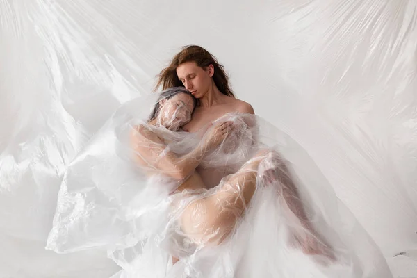 studio portrait of naked people inside big plastic bag, plastic pollution concept