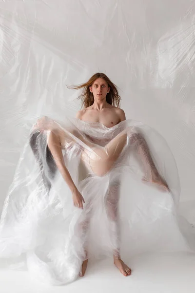 studio portrait of naked people inside big plastic bag, plastic pollution concept