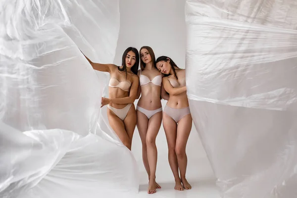 studio portrait of naked people inside big plastic bag, plastic pollution concept