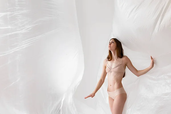 studio portrait of naked people inside big plastic bag, plastic pollution concept