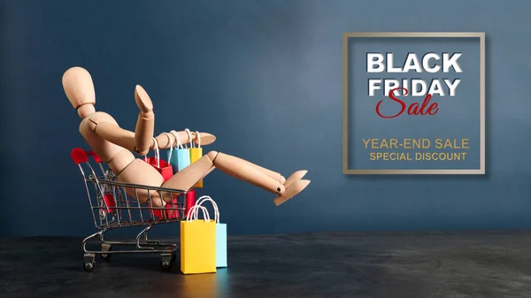 Black Friday Sprzedaż Drewniana Lalka Siedzi Koszyku Torbą Zakupy — Zdjęcie stockowe