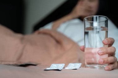 Hasta kadınların elindeki ilaç bir bardak su, sağlık ve ilaç iyileştirme konsepti - yumuşak odaklanma