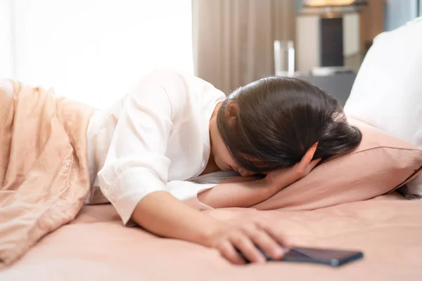 熟睡的女人睡觉时关掉智能手机的闹钟 — 图库照片