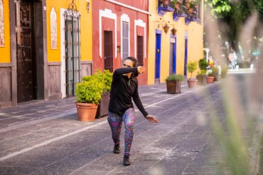 Genç Meksikalı kadın sokakta egzersiz yapıyor.