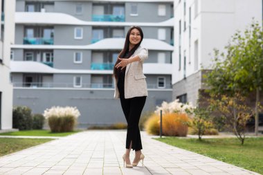 Modern bina arka planında poz veren güzel genç bir kadın