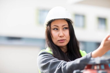 Asian woman engineer in white protective helmet examine construction field 