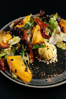 Balkabaklı sonbahar salatası ve siyah arka planda güneşte kurutulmuş domates.