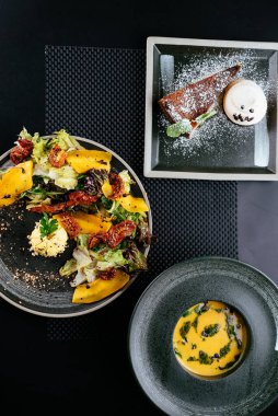 Balkabaklı sonbahar salatası ve siyah arka planda güneşte kurutulmuş domates.