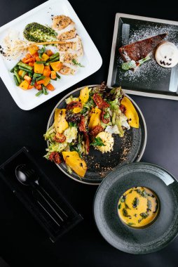 Balkabaklı sonbahar salatası ve siyah arka planda güneşte kurutulmuş domates.