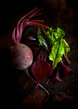 Siyah arka planda yaprakları olan kırmızı pancar.