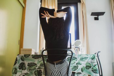 Genç bir kadın masada oturuyor ve bilgisayarla uğraşıyor.