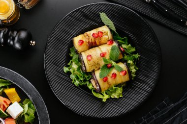 Arka planda sebzeli kızarmış patlıcan rulosu.