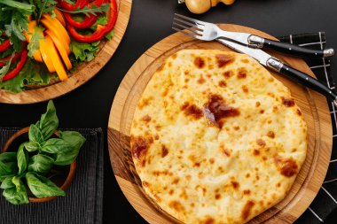 Gürcü peynirli tortilla, siyah arka planda sebzeler.