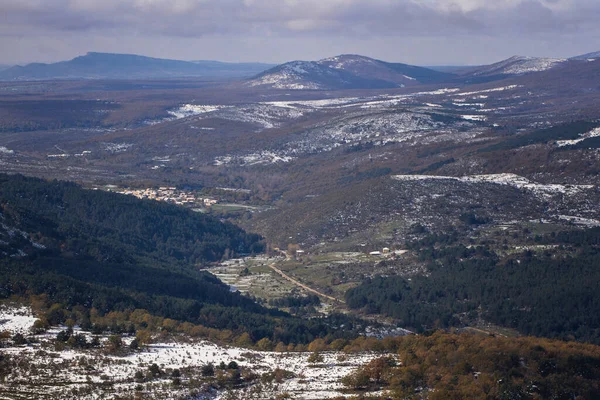 Snowy mountain with trees and village below