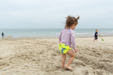 Küçük tatlı kız yazın kumsalda oynuyor.