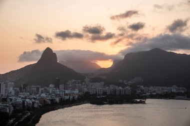 Şehir gölüne ve dağların ardında güzel günbatımına bakın, Rio de Janeiro, Brezilya