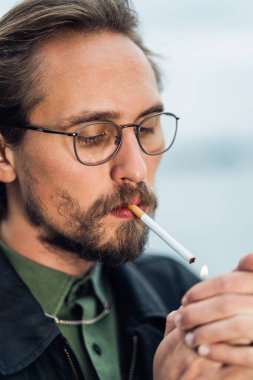 Sigara yakan genç bir adamın fotoğrafı.