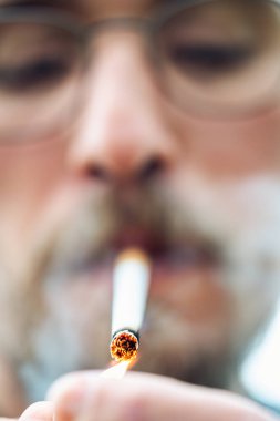 Sigara yakan genç bir adamın yakın plan fotoğrafı.