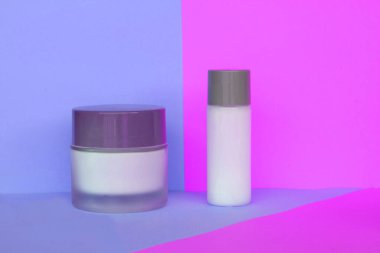 Mavi ve pembe arka planda iki şişe doğal krema. Vücut sütü ve yüz kremi. Sağlık ve Cilt Bakımı.