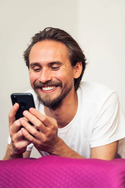 一个年轻英俊男子拿着手机微笑的照片 — 图库照片