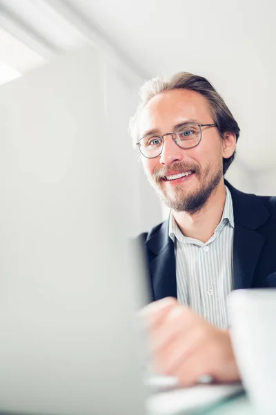 Foto Joven Guapo Enfocado Sonriente Sentado Junto Escritorio Trabajando Computadora —  Fotos de Stock