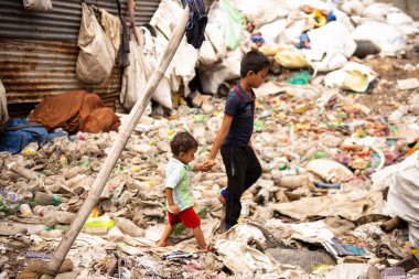 Çöplükte yürüyen iki çocuk.