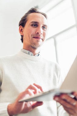 Genç adam taşınabilir bilgisayarına bakıyor..