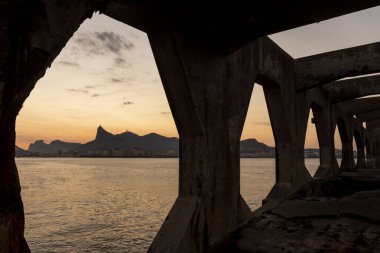 Rio de Janeiro, Brezilya 'daki kalenin beton yapısına çerçevelenmiş Corcovado Dağı' na güzel bir okyanus gün batımı manzarası