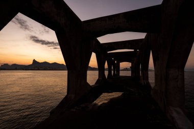 Rio de Janeiro, Brezilya 'daki kalenin beton yapısına çerçevelenmiş Corcovado Dağı' na güzel bir okyanus gün batımı manzarası