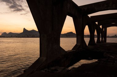 Rio de Janeiro, Brezilya 'daki kalenin beton yapısına çerçevelenmiş Corcovado Dağı' na güzel bir okyanus gün batımı manzarası