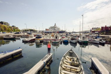 Kasabanın limanında güneşli bir günde teknelerin yanında isimsiz bir kadın duruyor.