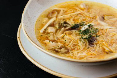 Erişteli tavuk çorbası ve dokulu siyah arka plan.