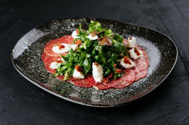 Siyah arka planda mermer sığır eti carpaccio