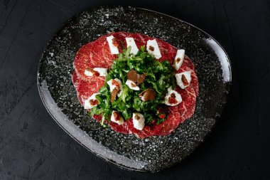 Siyah arka planda mermer sığır eti carpaccio