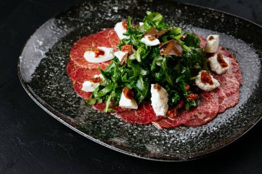 Siyah arka planda mermer sığır eti carpaccio