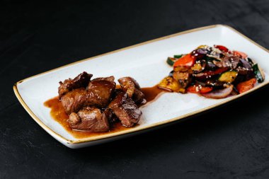 Siyah arka planda sebzeli biftek yahnisi.