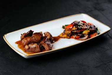 Siyah arka planda sebzeli biftek yahnisi.