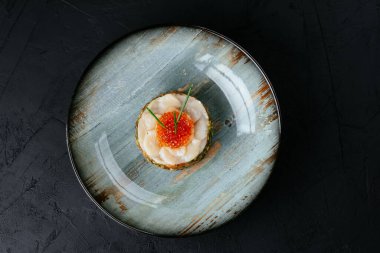 Siyah arka planda kırmızı havyarlı taze somon tartar.