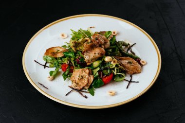 Siyah arka planda ızgara bıldırcın salatası.