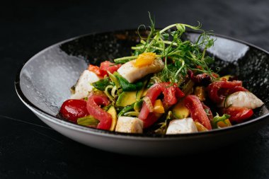 Siyah arka planda karides, sebze ve yengeç etli salata.