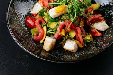 Siyah arka planda karides, sebze ve yengeç etli salata.