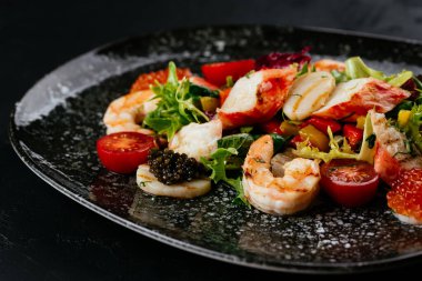 Siyah arka planda karides, sebze ve yengeç etli salata.