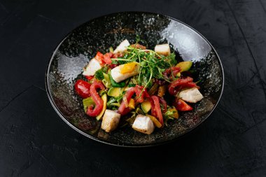 Siyah arka planda karides, sebze ve yengeç etli salata.