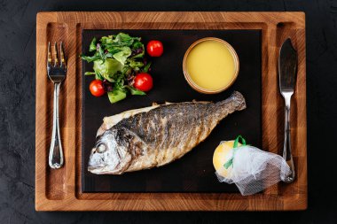 Dorado 'yu siyah arka planda sebzelerle kızarttım.