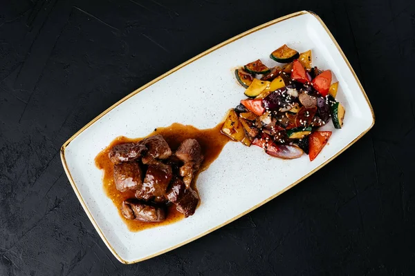 Siyah arka planda sebzeli biftek yahnisi.