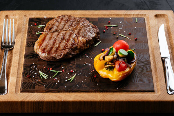 marbled beef steak with vegetables and sauce on a black background