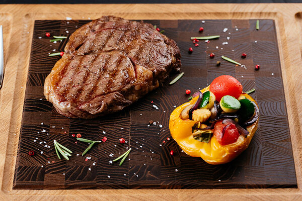 marbled beef steak with vegetables and sauce on a black background