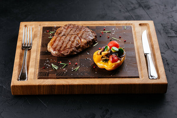 marbled beef steak with vegetables and sauce on a black background